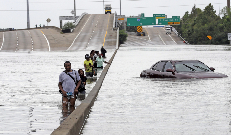 Evacuees wade down a flooded section of Interstate 610 in Houston as floodwaters from Tropical Storm Harvey rise Aug. 27.