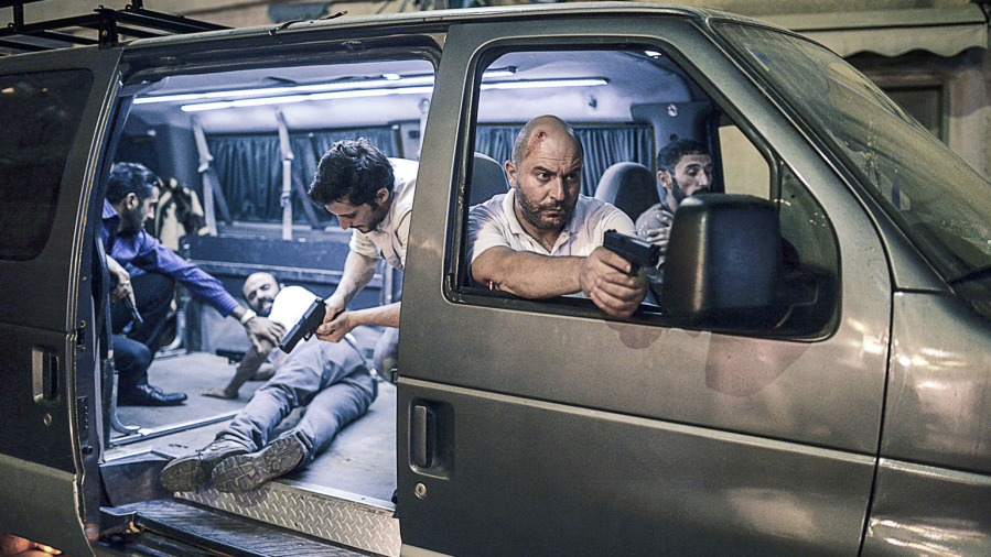 A scene from Season 1 of “Fauda,” including Lior Raz, the co-creator and actor portraying Doron Kavillio (right, pointing his gun out the window).