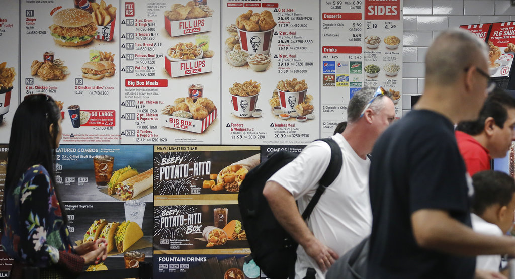 FILE - This Aug. 24, 2017 file photo, shows a KFC menu with calorie counts in New York. The Trump administration is moving ahead with a law from the Obama years that will require calorie counts to appear on foods served at restaurants, supermarkets, convenience stores and pizza delivery chains nationwide. The FDA posted recommendations Tuesday, Nov. 7, 2017 to help businesses comply with the law.