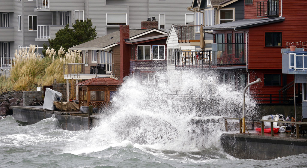 Waves hitting a breakwater send salt spray onto homes along Puget Sound in a windstorm Monday, Nov. 13, 2017, in Seattle. Thousands of people lost power in western Washington state after high winds swept through overnight, and the National Weather Service says more strong winds are expected. The weather service said Monday that many areas will continue to see gusts topping 50 mph, with even stronger winds on the coast and in north-central and northeastern Washington.