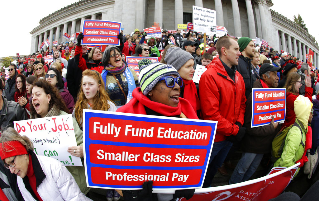 FILE - In this Jan. 16, 2017 file photo, Oveta Hunter, center, an elementary school teacher from Seattle, cheers and holds a sign during a rally in support of education funding at the Capitol in Olympia, Wash. The Washington State Supreme Court ruled Wednesday, Nov. 15, 2017, that while lawmakers have made progress, they are not on track to meet a court-imposed deadline to fully fund basic education, and will remain in contempt of court. (AP Photo/Ted S.