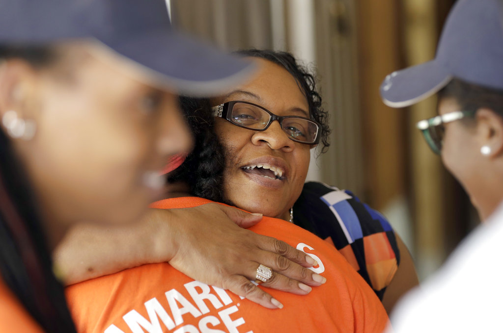 In this Nov. 17, 2017 photo, homeowner Arva Dorsey, center, hugs volunteers from Samaritan's Purse who were helping to rebuild her hurricane-damaged home in Houston. Dorsey usually hosts a large Thanksgiving dinner for family but is making other arrangements this year as she and her husband continue to recover from the storm damage. (AP Photo/David J.