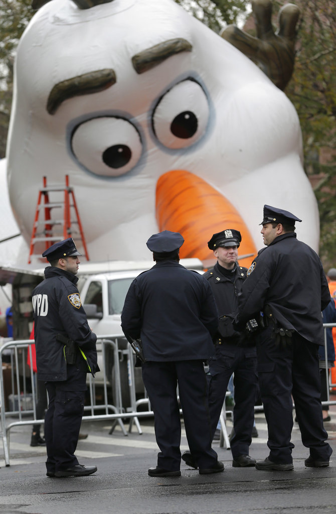 Police officers stand near the site where a large balloon of Olaf, from the animated film, "Frozen", is being inflated for the Thanksgiving Day parade in New York, Wednesday, Nov. 22, 2017. Sand-filled sanitation trucks and police sharpshooters will mix with glittering floats and giant balloons at a Macy's Thanksgiving Day Parade that comes in a year of terrible mass shootings and a deadly truck attack in lower Manhattan.