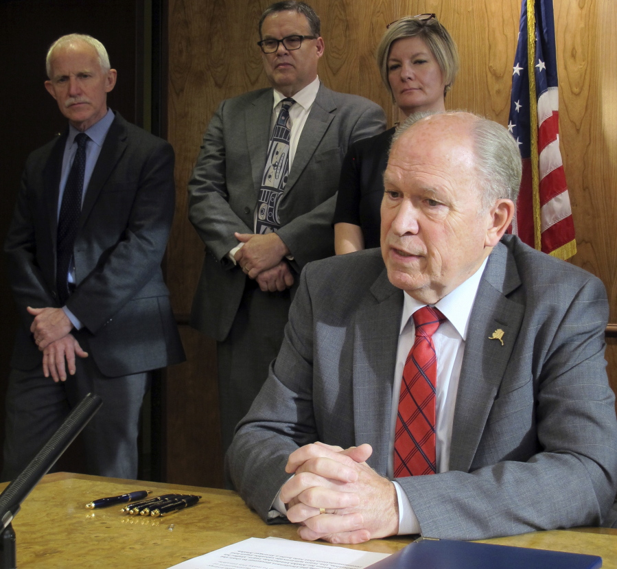Alaska Gov. Bill Walker speaks, as members of his administration look on, after signing an administrative order creating a team charged with making recommendations to address climate change on Tuesday in Juneau, Alaska. The team will include up to 15 public members yet to be appointed.