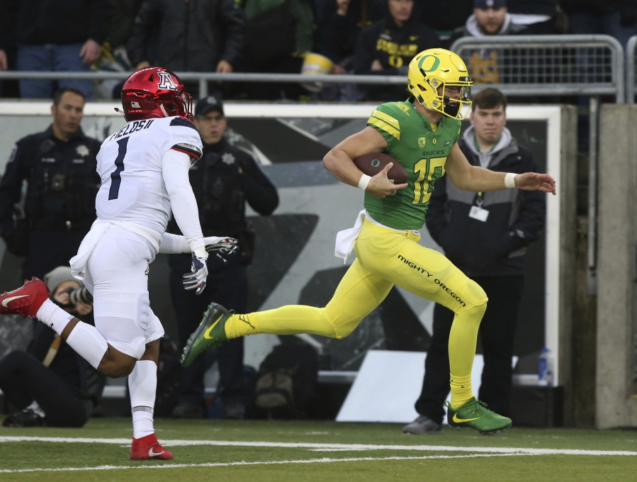 Oregon’s quarterback Justin Herbert, right, rushes for the end zone ahead of Arizona’s Tony Fields II for a touchdown during the first quarter of an NCAA college football game, Saturday, Nov. 18, 2017, in Eugene, Ore.