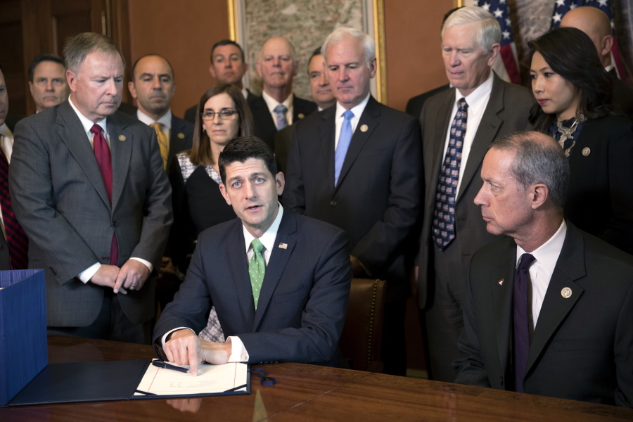 Speaker of the House Paul Ryan, R-Wis., joined by House Armed Services Committee members and Chairman Mac Thornberry, R-Texas, right, as Ryan puts his signature on the Defense spending bill before it goes to the president, on Capitol Hill in Washington, Thursday, Nov. 30, 2017. (AP Photo/J.