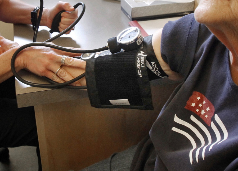 In this June 6, 2013, file photo, a patient has her blood pressure checked by a registered nurse in Plainfield, Vt. New medical guidelines announced Monday lower the threshold for high blood pressure, adding 30 million Americans to those who have the condition.