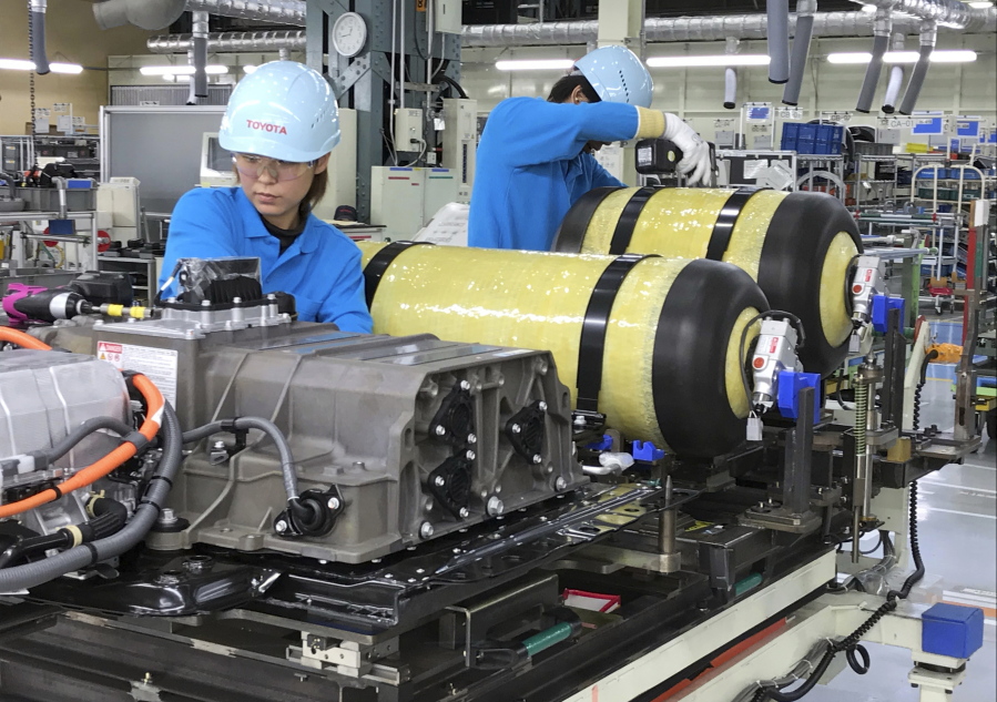 In this Oct. 30, 2017, photo, workers of Toyota Motor Corp. set hydrogen-stored tanks, in yellow, to be placed into a Mirai fuel cell vehicle at the automaker’s Motomachi plant, in Toyota, western Japan. Toyota is banking on a futuristic “electrification” auto technology called hydrogen fuel cells for its zero-emissions option. The Associated Press got a tour of Toyota’s Motomachi plant that assembles the Mirai fuel cell vehicle.