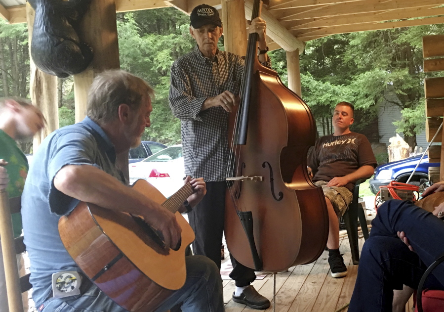Mike Baughman, center, plays the bass Oct. 12 with Sam Gibson, left, on guitar at a cabin in Herald, W.Va. Baughman is fighting a rare bile duct cancer he believes is a result of ingesting a parasite inside raw fish while serving in the Vietnam War.