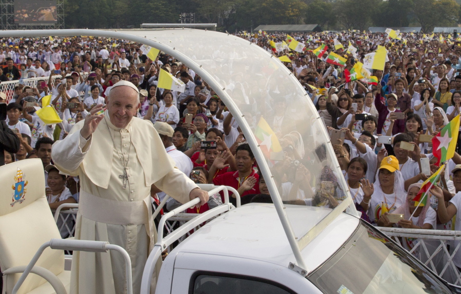 Pope Francis waves from Pope mobile as Myanmar Catholics wave flags ahed of the holy mass Wednesday in Yangon, Myanmar.