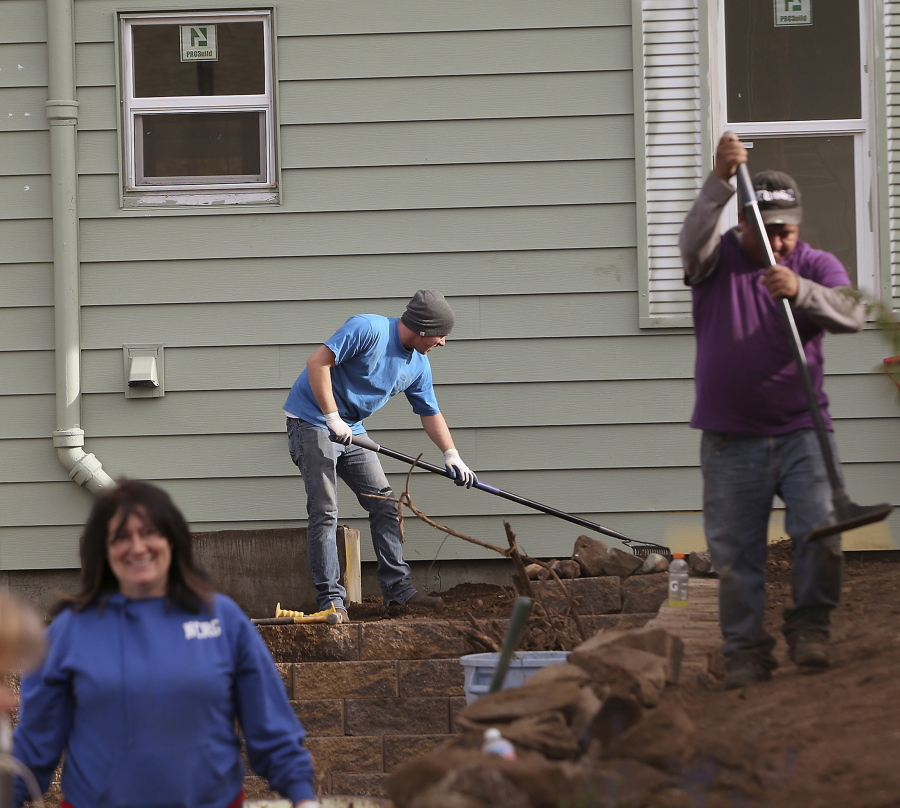 Volunteer Brad Storey, center, rakes Oct. 14 as fellow volunteers work on the landscaping of the Community Frameworks home in Bremerton. The home is the 20th residence rehabbed by the Northwest nonprofit, whose specialty is to flip distressed properties while keeping their sales prices affordable. (Meegan M.
