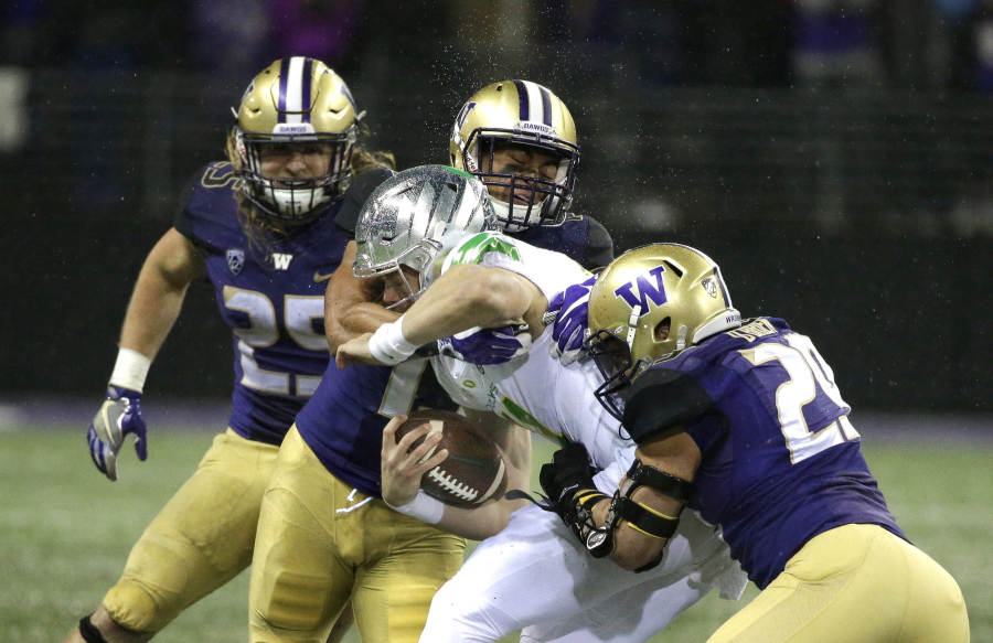 Oregon quarterback Braxton Burmeister is tackled by Washington linebackers Connor O’Brien, right, and Brandon Wellington, upper center, as linebacker Ben Burr-Kirven, left, looks on, in the first half of an NCAA college football game, Saturday, Nov. 4, 2017, in Seattle. (AP Photo/Ted S.
