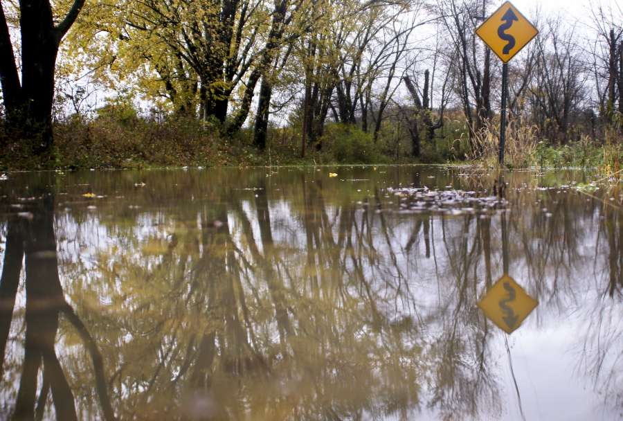 A road sign is reflected in the waters of the Connequenesing Creek that overflowed it’s banks along Evergreen Mill road after heavy rains from storms over Sunday into Monday in Harmony, Pa. Emergency officials suspect tornadoes and straight-line winds left behind a trail of damage Sunday that started in Indiana and continued through Ohio and into Pennsylvania.