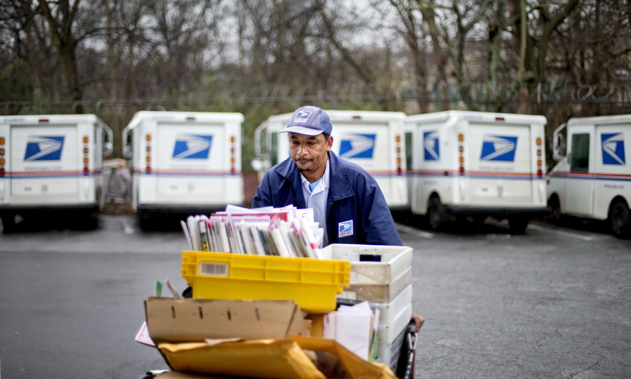 A U.S. Postal Service letter carrier gathers mail to load into his truck before making his delivery run in the East Atlanta neighborhood in Atlanta.