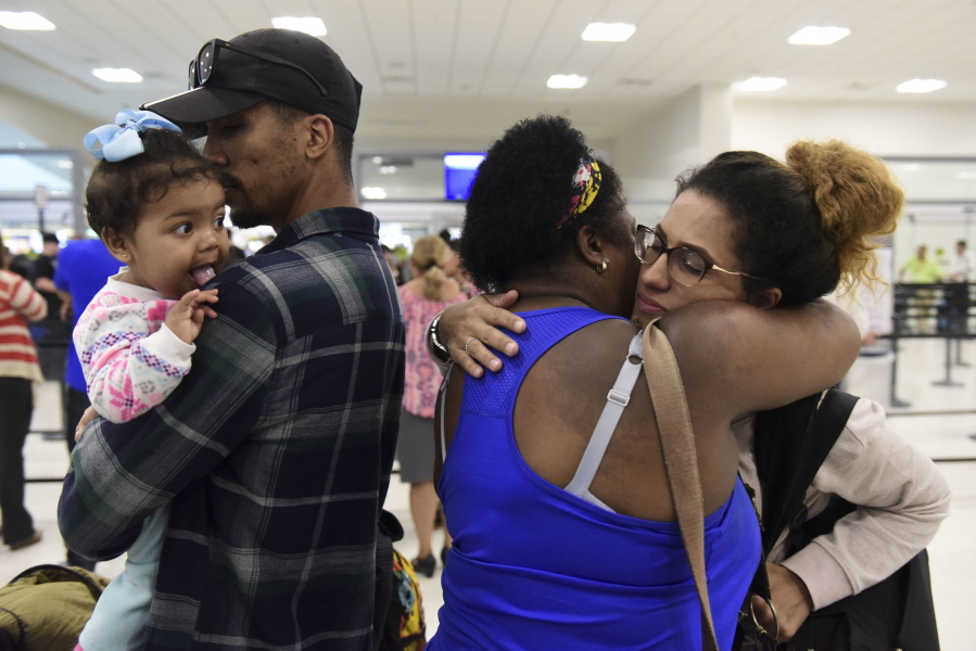 Waritza Alejandro embraces her mother-in-law Maritza Ortiz, before boarding a flight to Tampa with her husband Christian Vega and their daughter Tiana, in Carolina, Puerto Rico, on Wednesday. The couple lost their home to Hurricane Maria. The disaster wrought by Maria has set off an anguished debate across Puerto Rico, where friends, family and co-workers are arguing fiercely over the morality of leaving the blacked-out island vs. staying to fulfill a patriotic duty to rebuild.