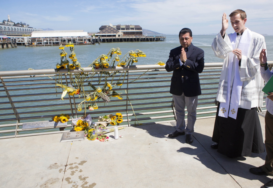 FILE - In this July 6, 2015 file photo, Father Cameron Faller, right, and Julio Escobar, of Restorative Justice Ministry, conduct a vigil for Kathryn Steinle on Pier 14 in San Francisco. A jury has reached a verdict Thursday, Nov. 30, 2017, in the trial of Mexican man at center of immigration debate in the San Francisco pier shooting.