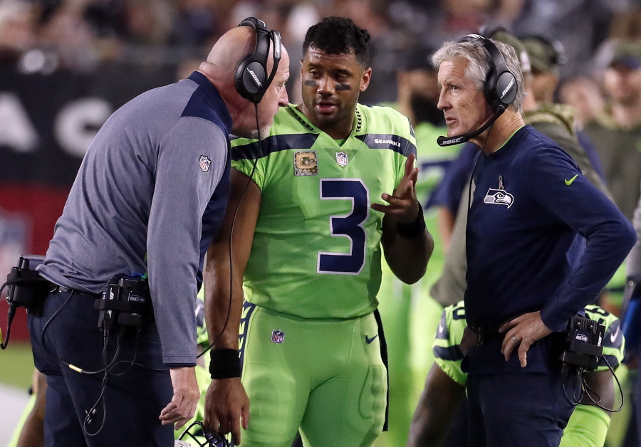 Seattle Seahawks quarterback Russell Wilson (3) speaks with head coach Pete Carroll, right, and assistant head coach Tom Cable during an NFL football game against the Arizona Cardinals in Glendale, Ariz.