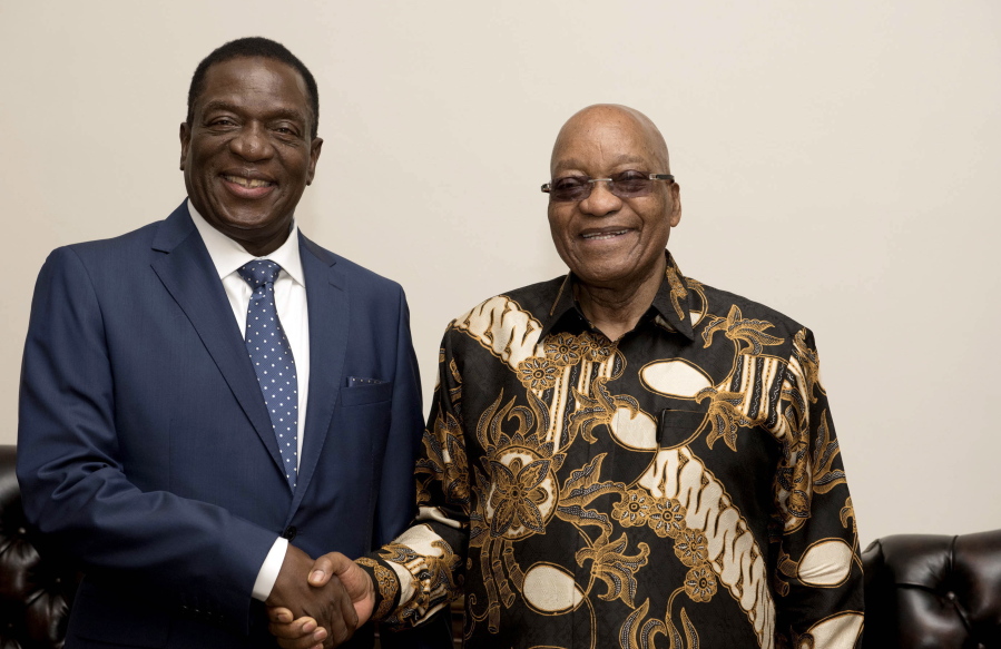 Former Vice President of Zimbabwe Emmerson Mnangagwa, left, shakes hands with South African President Jacob Zuma during a visit Wednesday to Pretoria, South Africa.