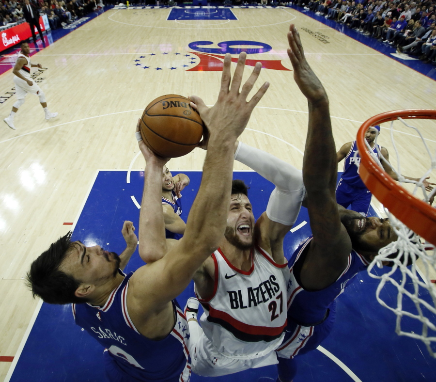 Portland’s Jusuf Nurkic, center, goes up for a shot between Philadelphia’s Dario Saric, left, and Amir Johnson.