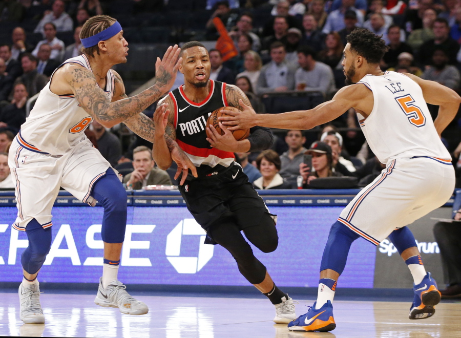 New York Knicks forward Michael Beasley (8) and Knicks guard Courtney Lee (5) defend Portland Trail Blazers guard Damian Lillard (0) during the second half of an NBA basketball game in New York, Monday, Nov. 27, 2017. The Trail Blazers defeated the Knicks 103-91.