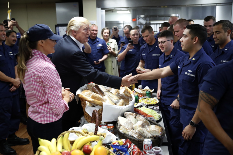 President Donald Trump, with first lady Melania Trump, greets and hands out sandwiches to members of the U.S. Coast Guard, at the Lake Worth Inlet Station, on Thanksgiving in Riviera Beach, Fla.