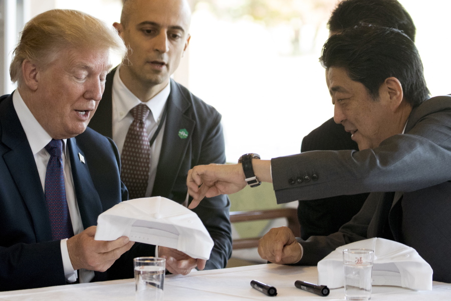 President Donald Trump, left, and Japanese Prime Minister Shinzo Abe sign hats that read “Donald and Shinzo, Make Alliance Even Greater” today at Kasumigaseki Country Club in Kawagoe, Japan.
