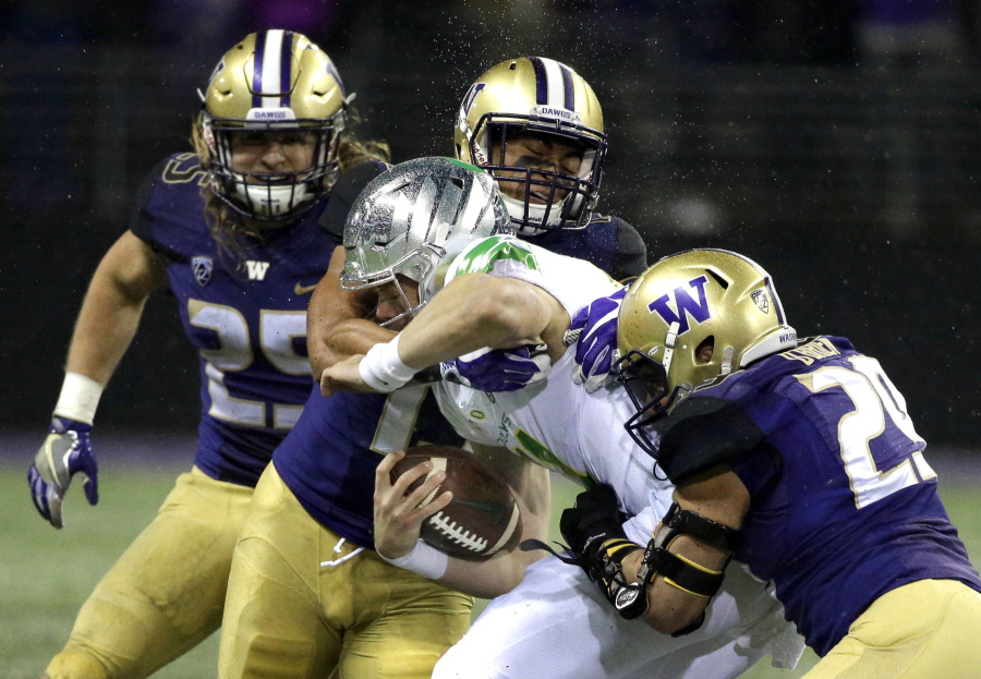 Oregon quarterback Braxton Burmeister is tackled by Washington linebackers Connor O’Brien, right, and Brandon Wellington, upper center. No. 9 Washington brings the best defense in the country into Friday’s matchup at Stanford. Ted S.