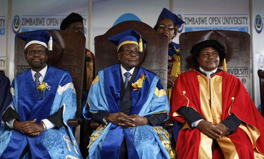 Zimbabwe’s President Robert Mugabe, center, sits for formal photographs with university officials, after presiding over a student graduation ceremony at Zimbabwe Open University on the outskirts of Harare, Zimbabwe, on Friday. Mugabe is making his first public appearance since the military put him under house arrest earlier this week.