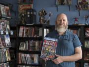Chris Simons, owner of I Like Comics, pauses for a photo with a copy of “Captain America No. 6” from September 1941. The rare comic is one of perhaps 100 in existence.