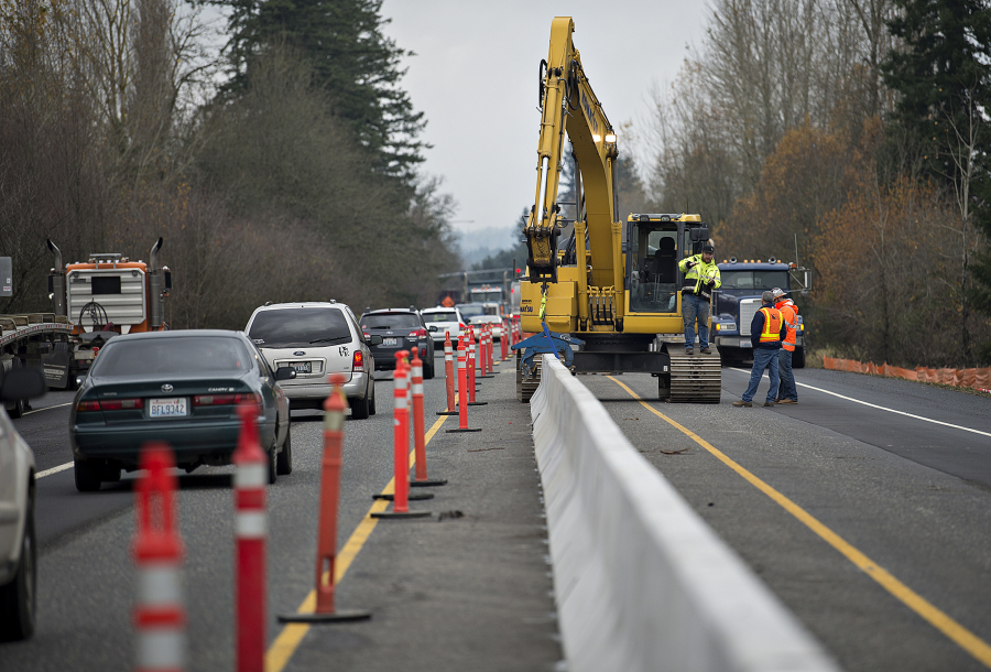 Motorists traveling north on state Highway 503, left, are routed around construction crews as they install a traffic barrier Friday afternoon in Battle Ground. The city is in the midst of its Congestion Relief Project at the intersection of highways 502 and 503, which sees around 50,000 drivers on an average weekday.