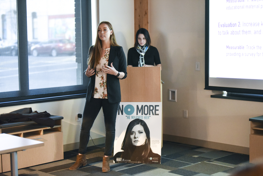 WSU Vancouver student Kelsie Reef, left, presents her team’s campaign to a group of judges and WSU Vancouver students Tuesday during the Washington Says No More campaign presentations, while her teammate Melanie Shelton prepares at the lectern behind her at Pacific Continental Bank in Vancouver.