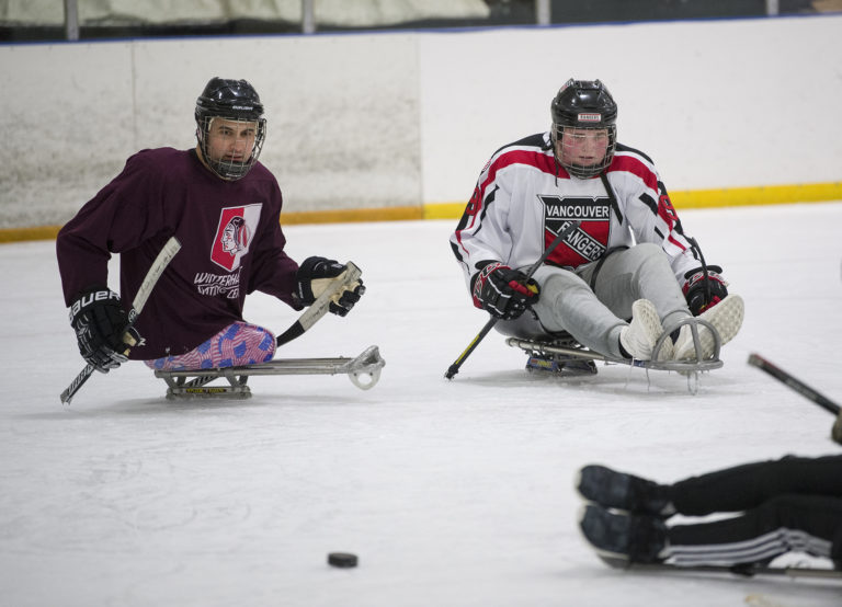 Paralympic sled hockey gold medalist Josh Sweeney, left, plays sled hockey with Connor Foppe, 16, at Mountain View Ice Arena, Wednesday December 6, 2017. Foppe suffered a stroke in April and has been regaining mobility on the right side of his body. His teammates joined him on sleds to practice with Sweeney and members of the Portland Winterhawks sled team.