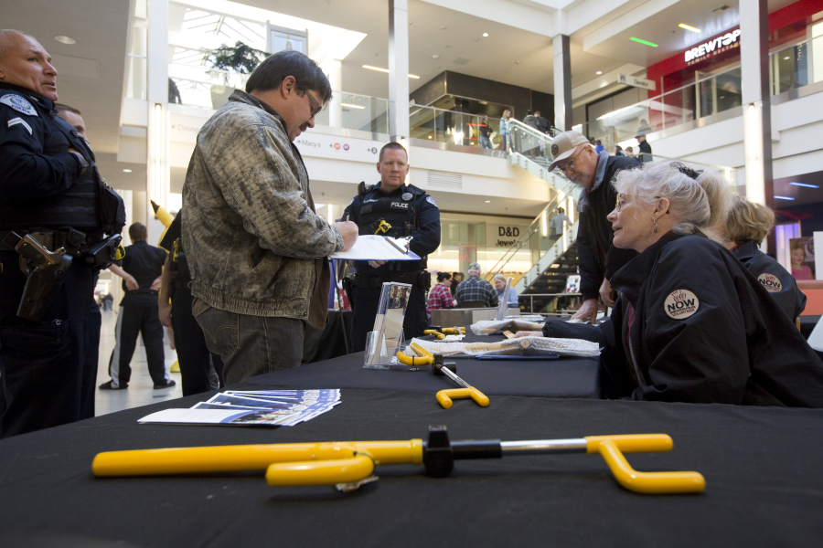 NOW volunteer Beth Christian, right, helps Karl Betersen get a free steering wheel lock Sunday in the Vancouver Mall. The Vancouver Police Department handed out the free locks as part of the department’s auto theft prevention program.