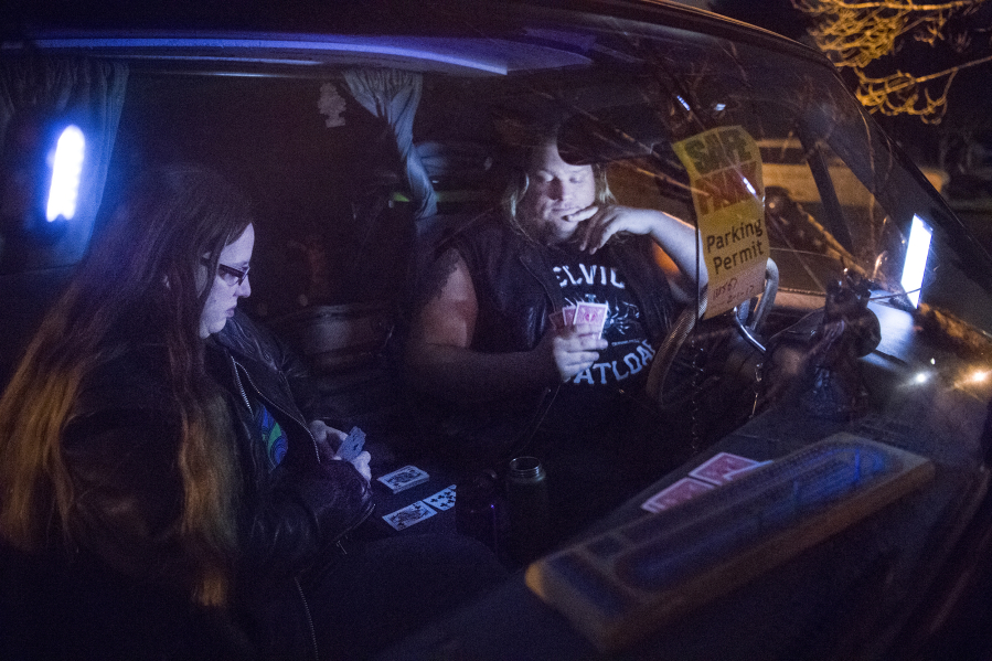 Shannon Medlin, 37, left, plays cribbage with her partner, who goes by his stage name, Thor Shreddington, 31, in their 1986 GMC Suburban. They’re taking part in the SafePark program, which permits people to park overnight in participating church parking lots. “I’m thankful to have a place like this,” Medlin said.