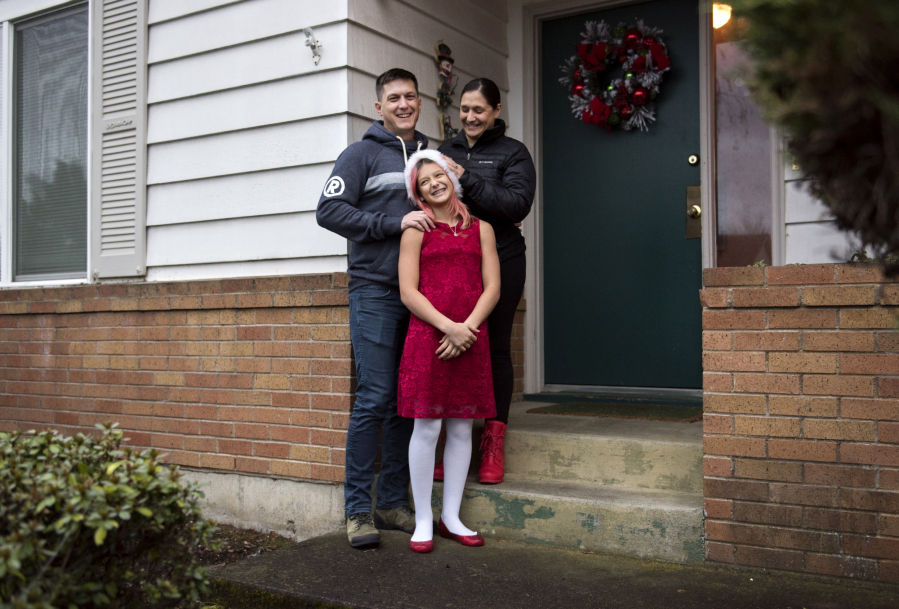 Will Mantz, left, and his wife, Jannea, right, stand outside their house with their daughter Ari. They rent their home and are hopeful the housing market will balance out soon so they can buy.
