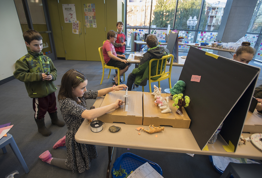 Reid Swank, 9, of Vancouver works with his sister Tayden, 10, as they film a stop-motion movie Wednesday afternoon at Vancouver Community Library. Students used an application on tablets for the project, which allowed them to take photos and stitch them together.