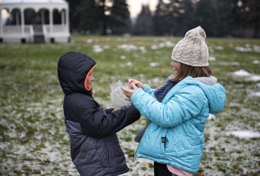 Lucca Pasquini, 7, left, and Layla Pasquini, 10, both of Santa Cruz, Calif., played with ice near the bandstand at Fort Vancouver on Tuesday. The siblings, who spent Christmas playing with ice and sledding down the street while visiting family in Vancouver, could see more wintry weather Wednesday morning, when the forecast calls for freezing rain.