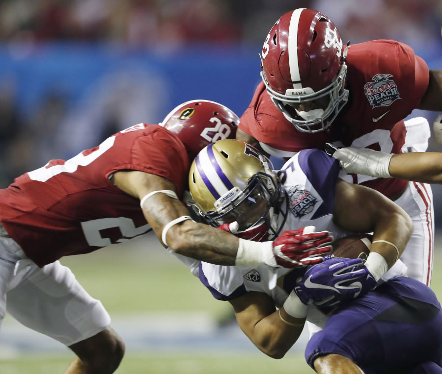 Washington running back Myles Gaskin (9) is tackled by Alabama defenders in last yera’s Peach Bowl. This year, Gaskin and other Husky returners are no longer in awe of playing in a big-time bowl game.
