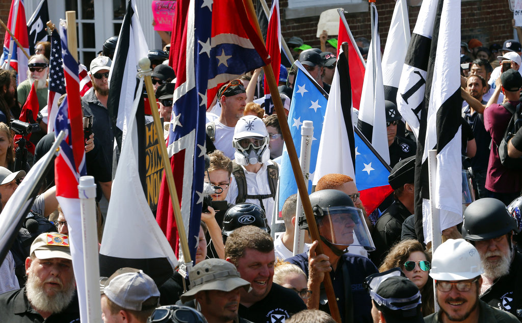 FILE - In this Saturday, Aug. 12, 2017, file photo, white nationalist demonstrators walk into the entrance of Lee Park surrounded by counter demonstrators in Charlottesville, Va.  A former federal prosecutor says the law enforcement response to a white nationalist rally this summer in Charlottesville that erupted in violence was a series of failures. The findings of former U.S. Attorney Tim Heaphy's monthslong investigation were unveiled Friday, Dec. 1. City officials asked him to conduct the review after facing scathing criticism over the Aug.