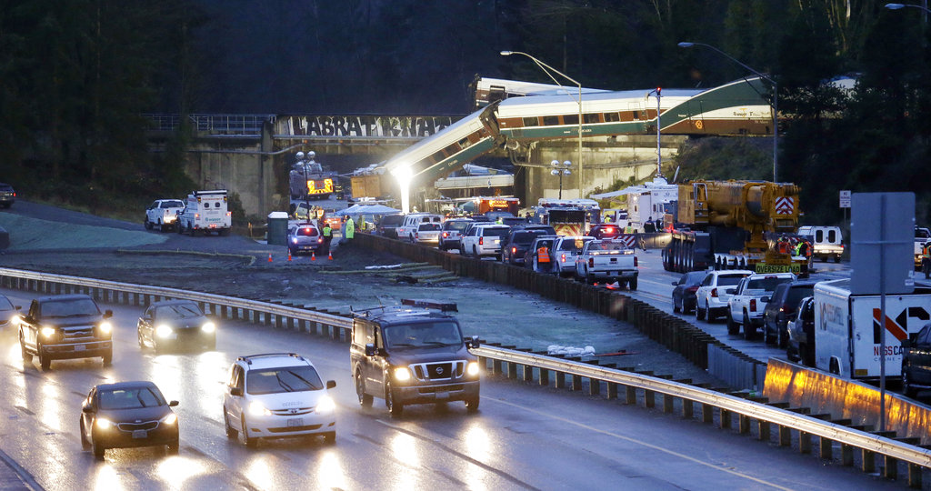 Traffic moves along northbound Interstate 5, left, as southbound lanes are filled with emergency vehicles near the scene of an Amtrak train crash Monday, Dec. 18, 2017, in DuPont, Wash. The Amtrak train making the first-ever run along a faster new route hurtled off the overpass Monday near Tacoma and spilled some of its cars onto the highway below, killing some people, authorities said.