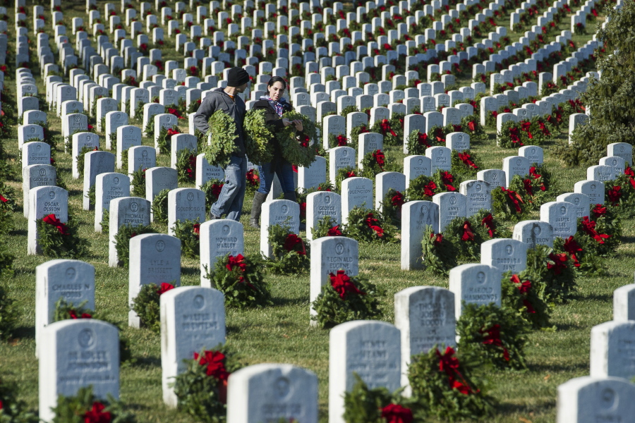 Marine Corp SSG Andrew Christman, left, and Ashley Robinson, of Chambersburg, Pa., carry wreaths as they participate in Wreaths Across America, placing remembrance wreaths on headstones at Arlington National Cemetery on Saturday in Arlington, Va.