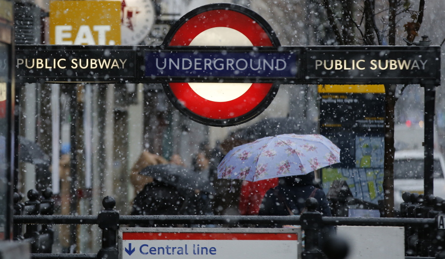 A woman walks away from Notting Hill underground station as snow falls in London Sunday, Dec.10, 2017.
