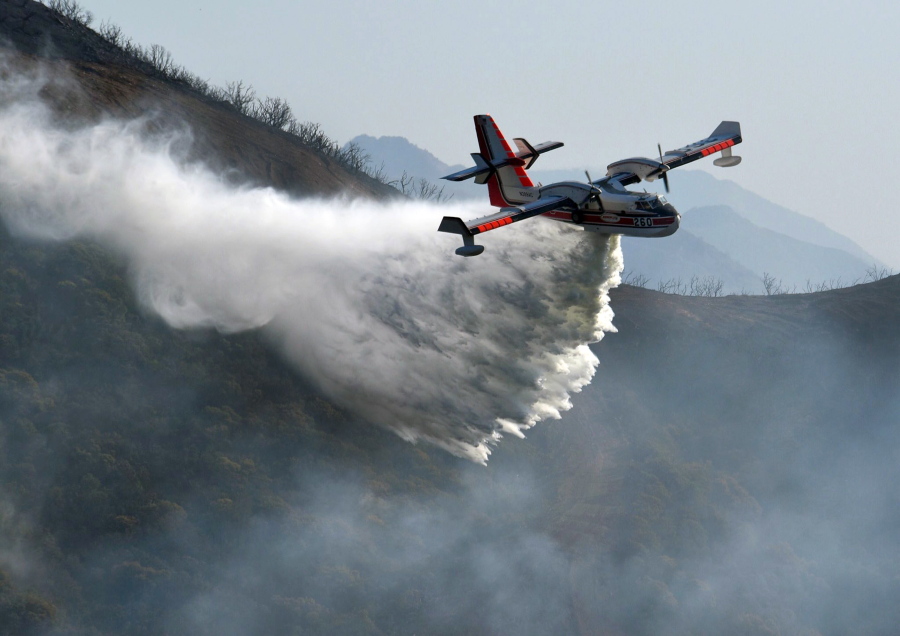 In this photo provided by the Santa Barbara County Fire Department, a Bombardier 415 Super Scooper makes a water drop on hot spots along the hillside east of Gibraltar Road in Santa Barbara, Calif., Sunday morning, Dec. 17, 2017. One of the largest wildfires in California history is now 40 percent contained but flames still threaten coastal communities as dry, gusty winds are predicted to continue.