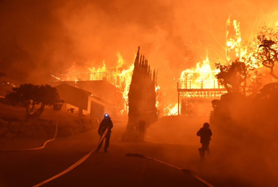 Ventura County Fire Department firefighters work to put out a blaze burning homes early Tuesday in Ventura, Calif. Authorities said the blaze broke out Monday and grew wildly in the hours that followed, consuming vegetation that hasn’t burned in decades.