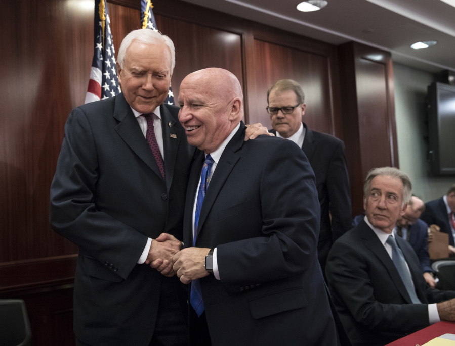 House Ways and Means Committee Chairman Kevin Brady, R-Texas, center, embraces Senate Finance Committee Chairman Orrin Hatch, R-Utah, left, as House and Senate conferees after GOP leaders announced they have forged an agreement on a sweeping overhaul of the nation’s tax laws, on Capitol Hill in Washington, Wednesday, Dec. 13, 2017. Rep. Richard Neal, D-Mass., ranking member of the House Ways and Means Committee, looks on at far right. Democrats objected to the bill and asked that a final vote be delayed until Senator-elect Doug Jones of Alabama is seated. (AP Photo/J.