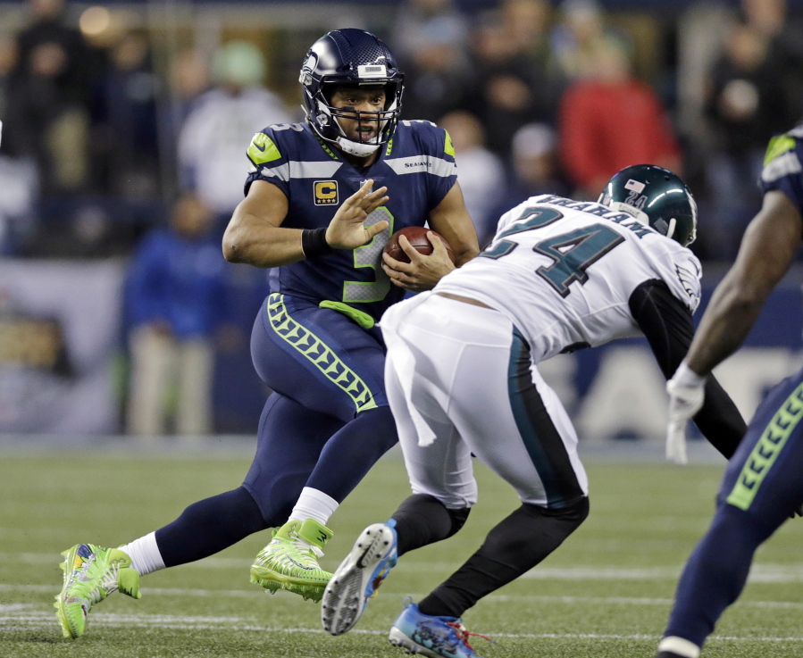Seattle Seahawks quarterback Russell Wilson, left, scrambles as Philadelphia Eagles’ Corey Graham (24) moves in during the first half of an NFL football game, Sunday, Dec. 3, 2017, in Seattle.
