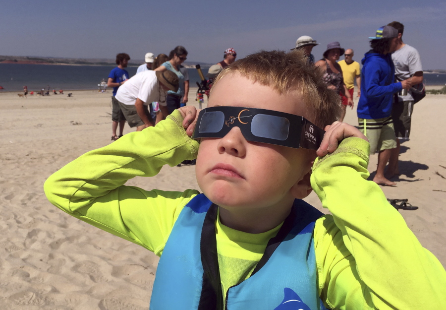 FILE - In this Aug. 21, 2017 file photo, Jack Kvenild, 5, of Laramie, Wyo., watches the eclipse onset at Glendo Reservoir in near Glendo in east-central Wyoming. An economic analysis of last summer’s total eclipse found that nearly 192,000 people traveled to Wyoming to view the event. In addition, the study released Monday, Dec. 11 by the state Office of Tourism estimated that the celestial event boosted the state’s economy by an estimated $63.5 million.