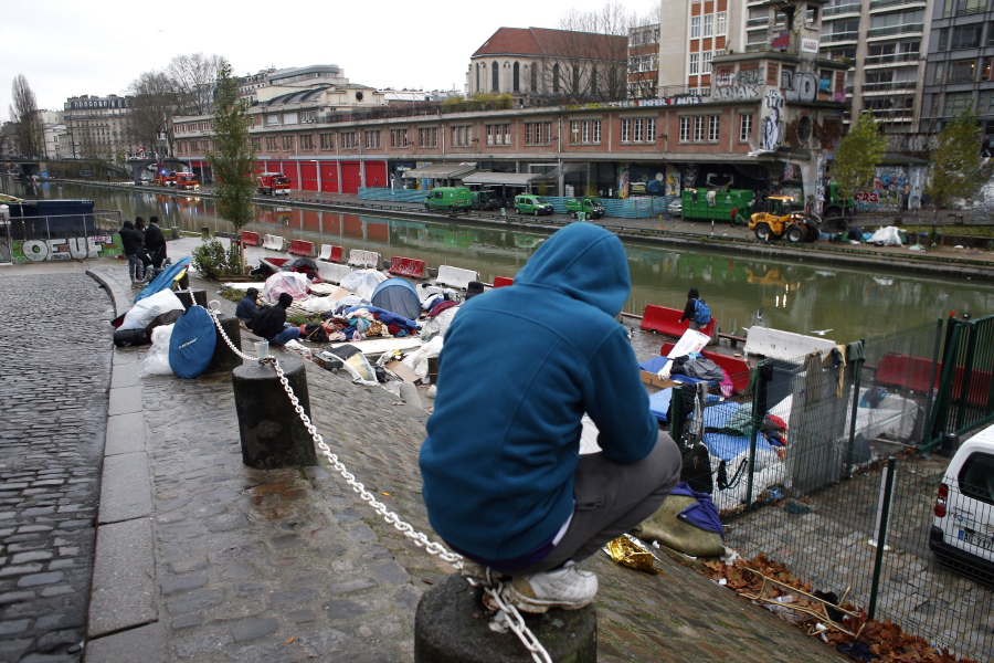Migrants sit by a makeshift camp in Paris on Thursday. The French government is scrambling to meet President Emmanuel Macron’s deadline to get migrants off France’s streets by year’s end.