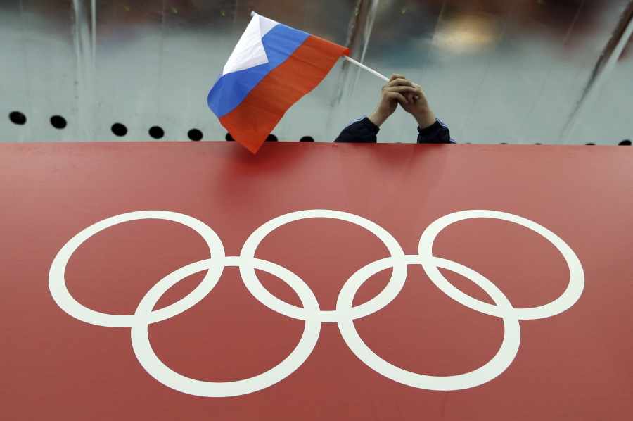 FILE - In this Feb. 18, 2014, file photo, a Russian skating fan holds the country's national flag over the Olympic rings before the start of the men's 10,000-meter speedskating race at Adler Arena Skating Center during the 2014 Winter Olympics in Sochi, Russia. Russia could be banned from competing at the Pyeongchang Olympics. The decision will come on Tuesday, Dec. 5, 2017 when the International Olympic Committee executive board meets in Lausanne, less than nine weeks before the games open on Feb. 9 in South Korea. (AP Photo/David J.