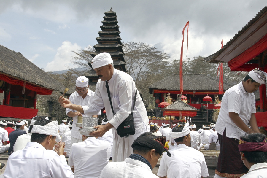 Hindu priests give holy water to worshipers during a prayer at a temple located a few kilometers (miles) from the crater of the Mount Agung volcano in Karangasem, Bali, Indonesia, Sunday, Dec. 3, 2017. Authorities have told tens of thousands of people to leave an area extending 10 kilometers (6 miles) from the volcano as it belches volcanic materials into the air. Mount Agung’s last major eruption in 1963 killed about 1,100 people.